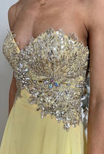 Load image into Gallery viewer, Tony Bowls TON115507 Prom gown has an A-Line style with Empire waist, strapless, chiffon overlay, fully beaded bodice, fully lined , Zipper closure. yellow
